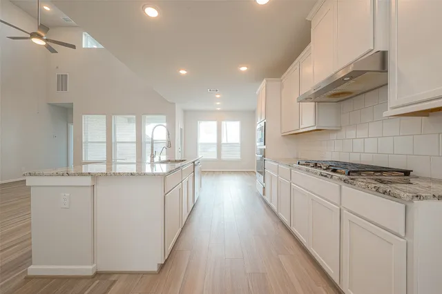 a kitchen with stainless steel appliances a sink stove and cabinets