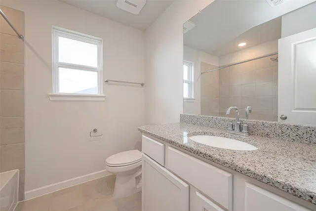 a bathroom with a granite countertop sink a toilet and a mirror