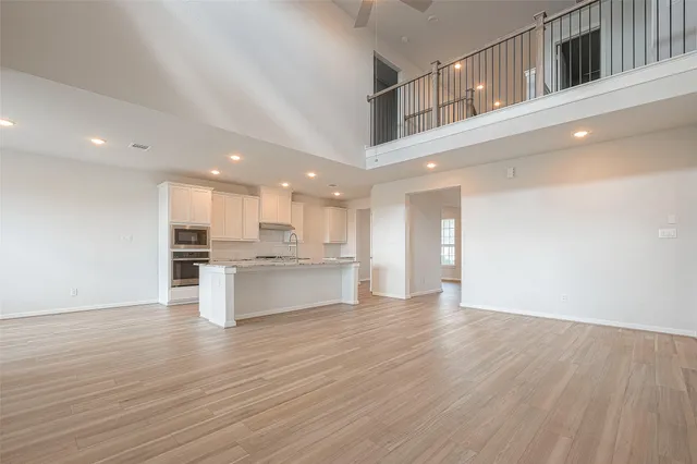 a large white kitchen with kitchen island a sink wooden floor and a refrigerator