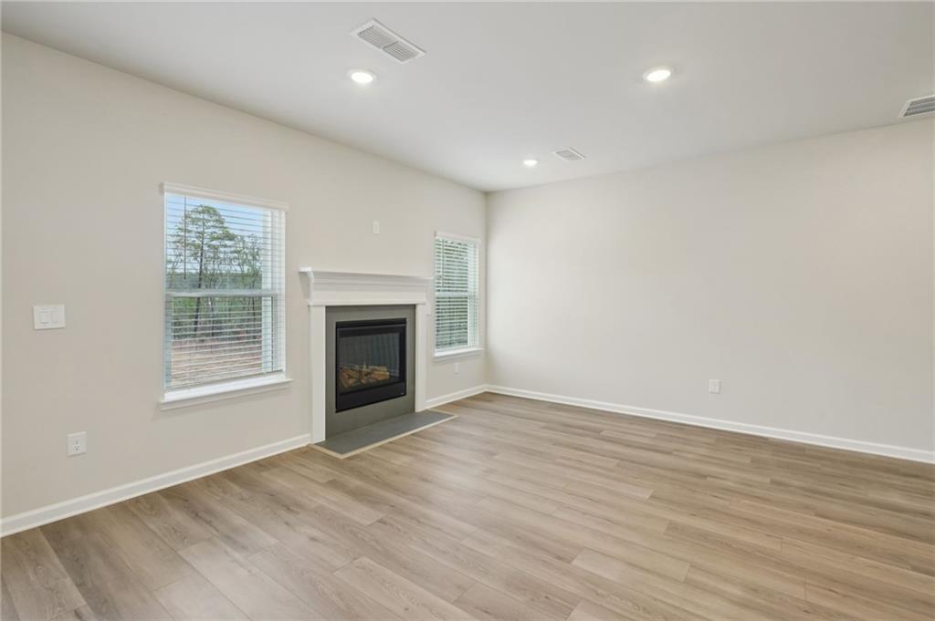 1458 High Fls Lane Grayson, GA 30017 - Photo 6 of 42 an empty room with wooden floor fireplace and windows