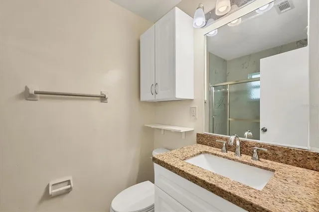 a bathroom with a granite countertop sink mirror vanity and toilet