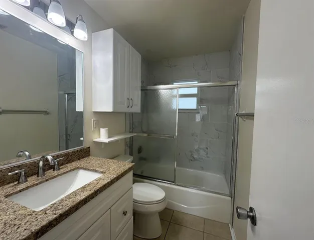 a bathroom with a granite countertop sink a toilet and shower