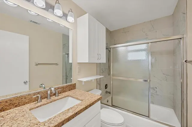 a bathroom with a granite countertop sink toilet and shower