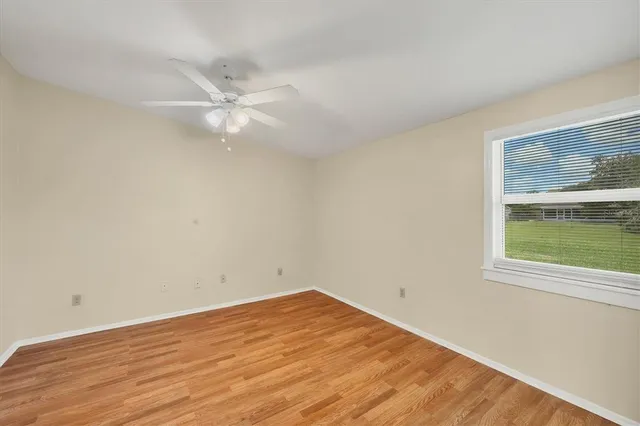 an empty room with a window and a ceiling fan