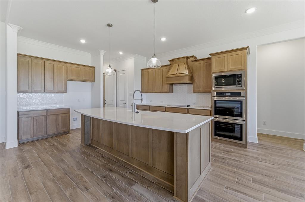 815 Vly Rdg Road Van Alstyne, TX 75495 - Photo 14 of 29 Spacious kitchen featuring a large central island with a solid surface countertop, light wood-finish cabinetry, a built-in double oven, and a patterned tile backsplash