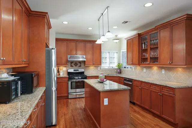 a kitchen with stainless steel appliances granite countertop wooden cabinets a stove top oven a sink and dishwasher