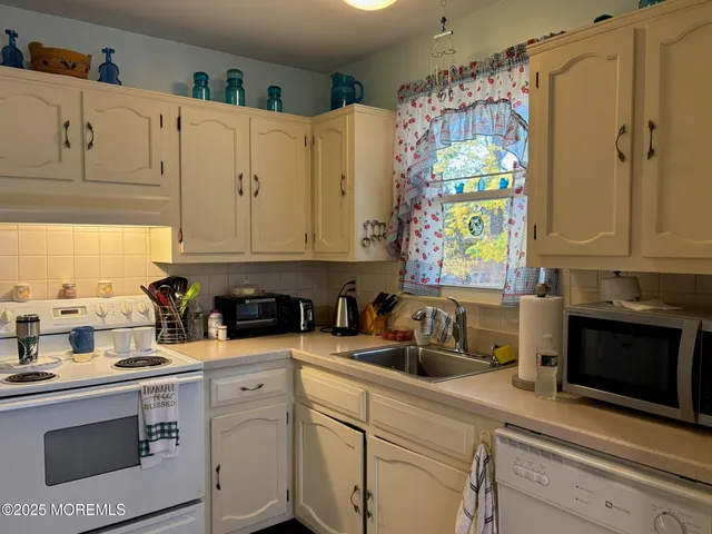 a kitchen with stainless steel appliances white cabinets a sink and a window