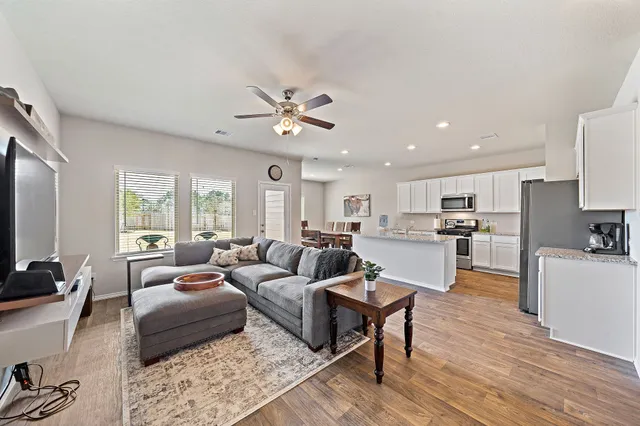 a living room with furniture kitchen view and a large window