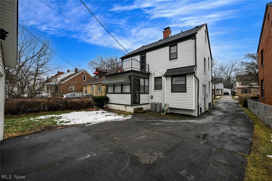 3699 Bainbridge Road Cleveland Heights, OH 44118 - Photo 2 of 37 Rear exterior featuring a screened porch, upper-level balcony with metal railing, white painted brick and siding, and an asphalt driveway