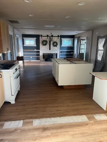 a view of living room kitchen with stainless steel appliances wooden floor and window