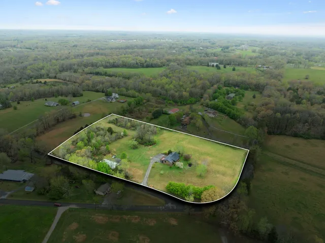 an aerial view of a houses with outdoor space and trees all around