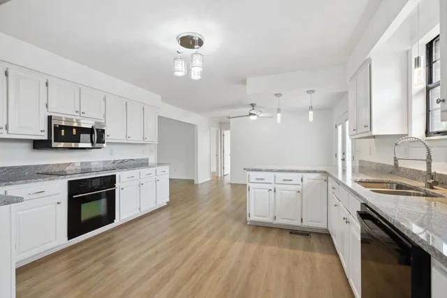 a large kitchen with cabinets stove top oven and sink