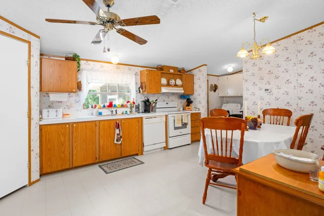a kitchen with stainless steel appliances kitchen island granite countertop a sink a stove a dining table and chairs with wooden floor