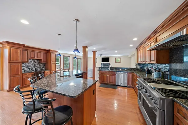a kitchen with stainless steel appliances granite countertop a stove a sink dishwasher and a refrigerator with wooden floor