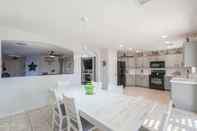 a kitchen with stainless steel appliances kitchen island granite countertop a refrigerator a stove top oven a sink dishwasher and white cabinets with wooden floor