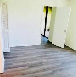 an empty room with wooden floor and mirror