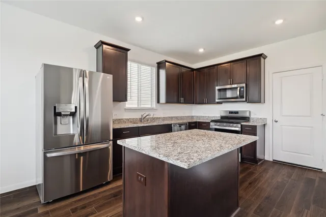 a kitchen with a refrigerator a microwave a sink and a stove with wooden floor