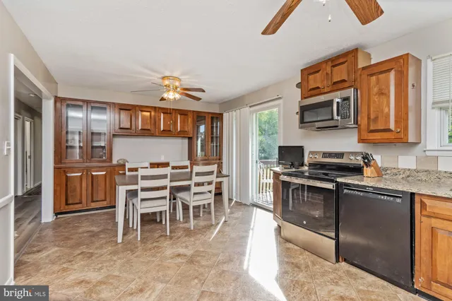 a kitchen with stainless steel appliances granite countertop a stove top oven a sink a dining table and chairs