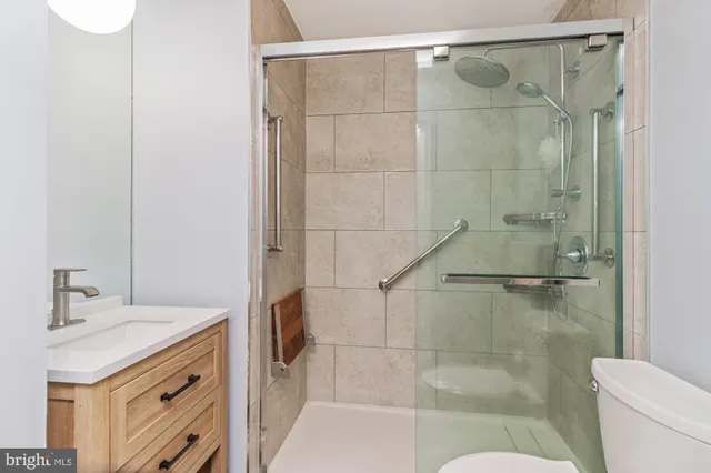 a bathroom with a granite countertop shower a sink and toilet