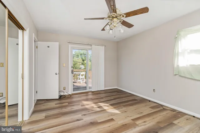 an empty room with a chandelier fan and windows