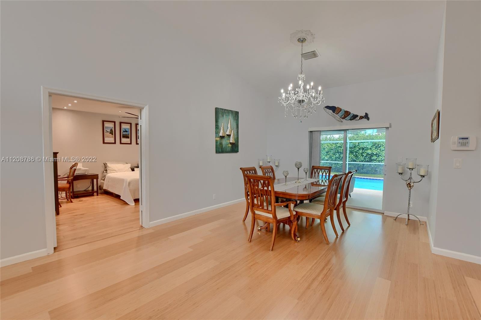9580 Carousel Circle South Boca Raton, FL 33434 - Photo 7 of 35 a dining room with wooden floor a chandelier a wooden table and chairs