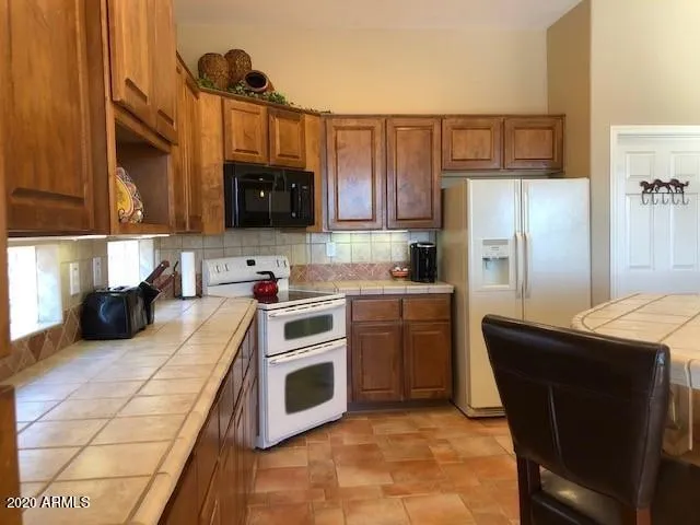 a kitchen with granite countertop a refrigerator stove and microwave