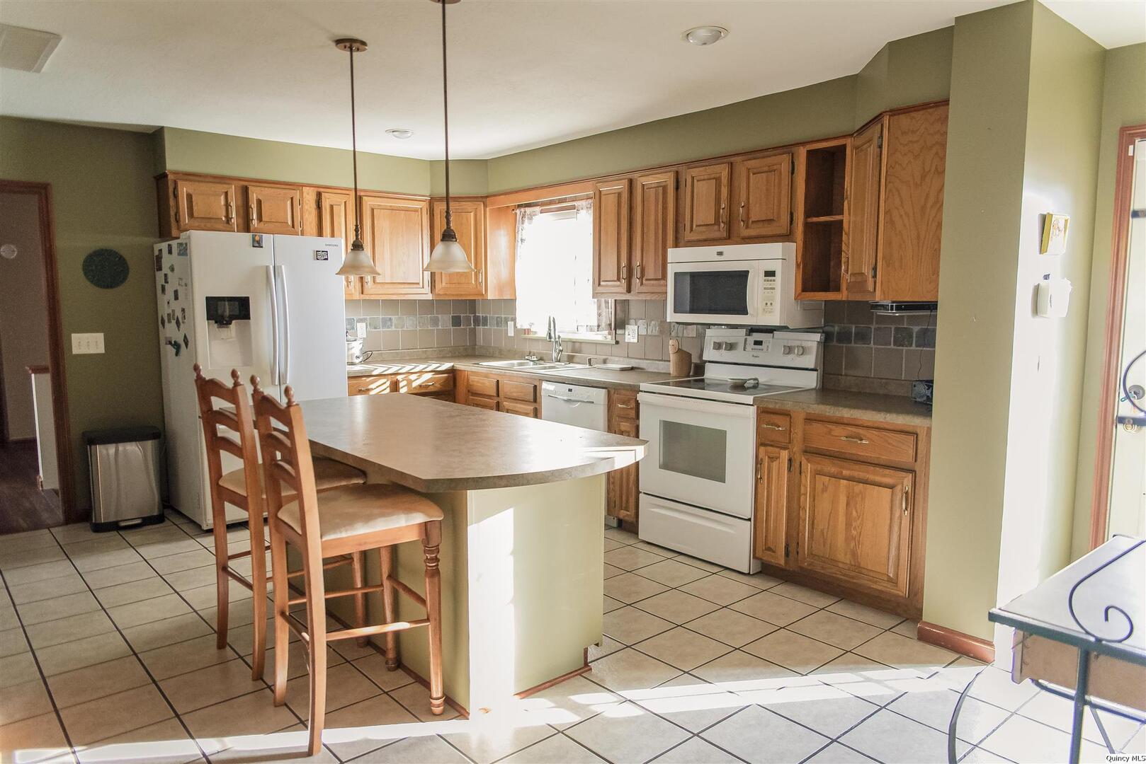 2208 Cherry Lane Quincy, IL 62301 - Photo 5 of 10 a kitchen with stainless steel appliances granite countertop a stove a sink dishwasher a refrigerator with a dining table and chairs with wooden floor