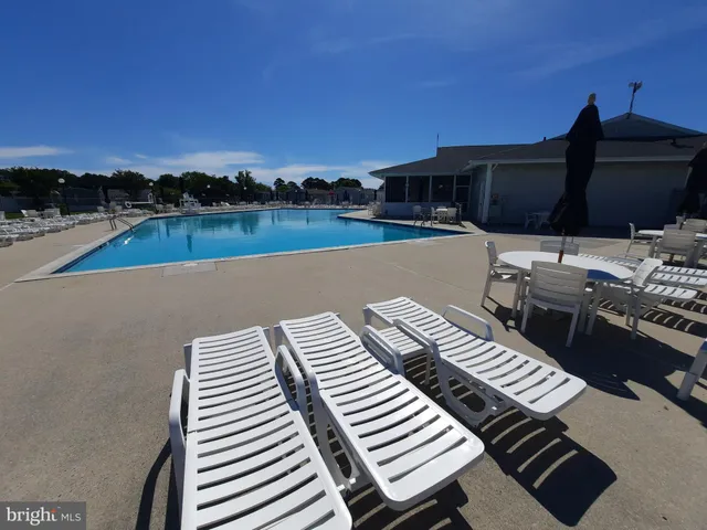 a view of a swimming pool with lawn chairs under an umbrella
