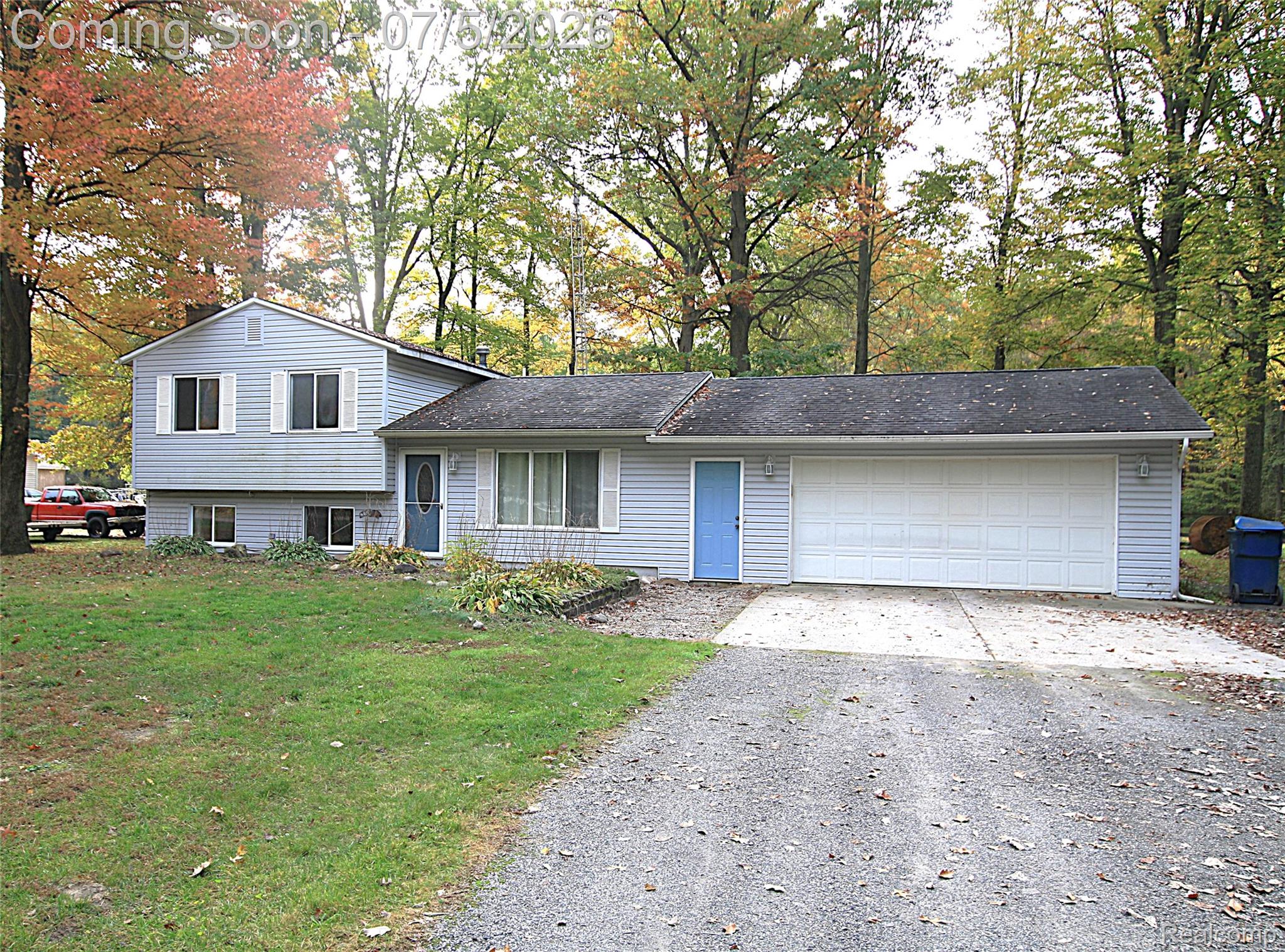 12403 Willard Road Montrose, MI 48457 - Photo 5 of 30 Tri-level home with driveway, a front yard, an attached garage, and view of scattered trees