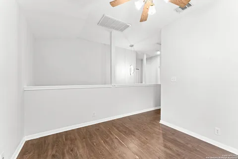 an empty room with wooden floor fan and window