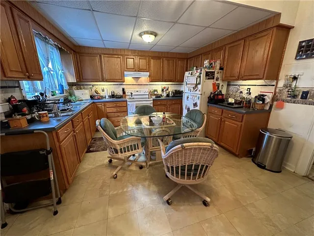 a kitchen with granite countertop a sink a stove a refrigerator cabinets and dining table