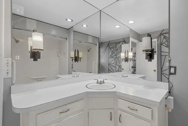 a bathroom with a sink a faucet a mirror and a shower