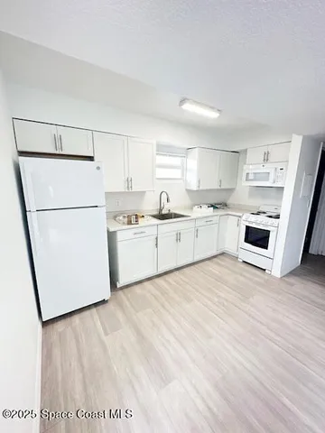 a kitchen with stainless steel appliances granite countertop a refrigerator sink and white cabinets