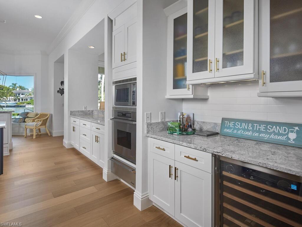 377 Pirates Bight Naples, FL 34103 - Photo 15 of 44 a kitchen with stainless steel appliances white cabinets and wooden floors