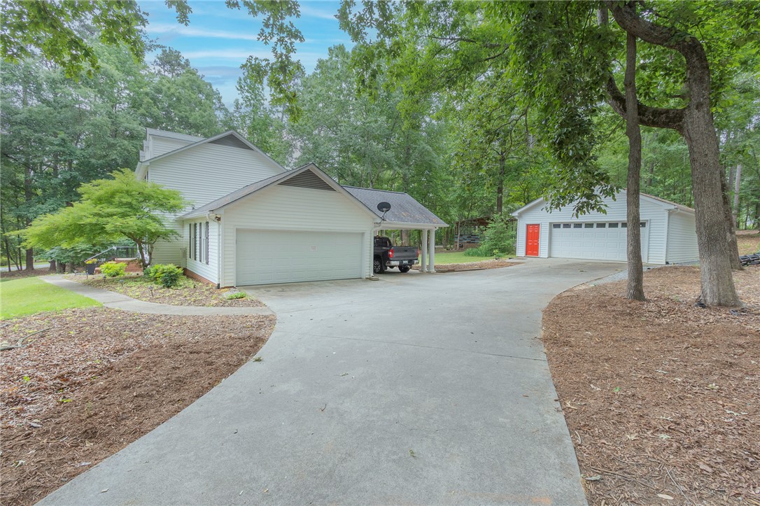 203 Oak Hollow Pendleton, SC 29670 - Photo 34 of 50 A long paved driveway leads to a two-car garage with an additional covered parking space.