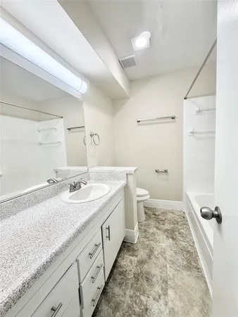 a spacious bathroom with a granite countertop sink a toilet a mirror and shower