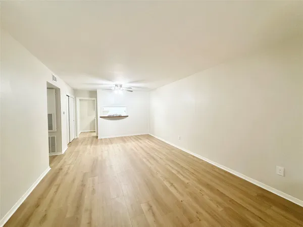 an empty room with wooden floor cabinet and windows