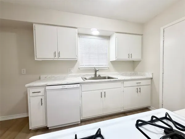 a kitchen with granite countertop white cabinets and a stove