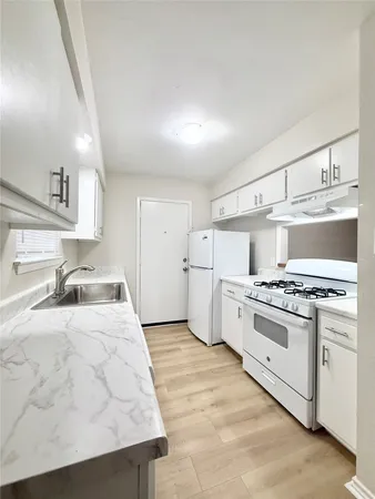 a kitchen with granite countertop a sink a stove and refrigerator