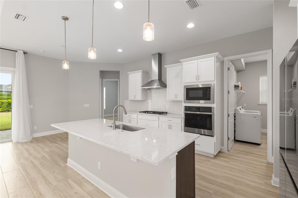 12048 Southwest 35th Place Gainesville, FL 32608 - Photo 13 of 53 a kitchen with stainless steel appliances a stove a sink a center island a refrigerator and a wooden floor