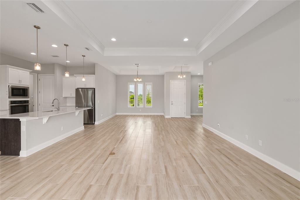 12048 Southwest 35th Place Gainesville, FL 32608 - Photo 8 of 53 a view of an empty room and kitchen with furniture wooden floor