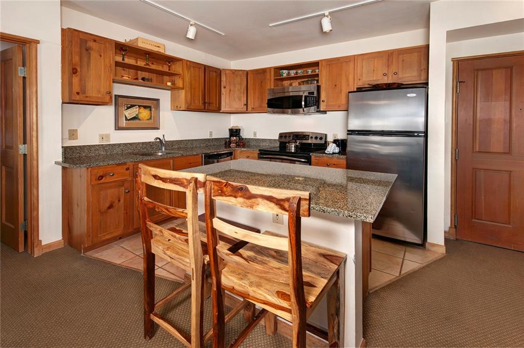 195 River Run Road, Unit 8017 Keystone, CO 80435 - Photo 7 of 32 a kitchen with stainless steel appliances granite countertop a stove top oven a refrigerator a sink and a granite counter tops