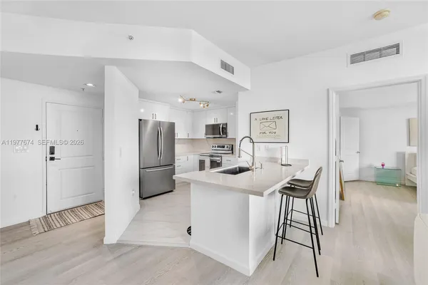 a kitchen with stainless steel appliances kitchen island a table chairs and refrigerator