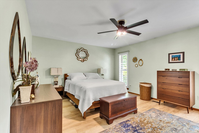 2863 Fallentine Road Sandy, UT 84093 - Photo 30 of 48 Spacious bedroom featuring light-toned wood-finish flooring, a contemporary ceiling fan with integrated lighting, and a window with white louvered shutters