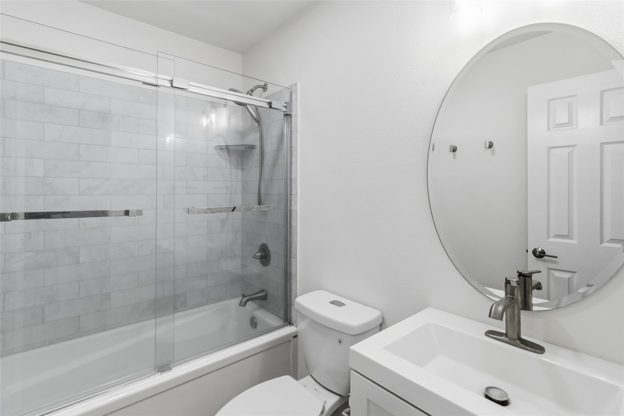 326 Pine View Loop Bastrop, TX 78602 - Photo 14 of 30 A pristine bathroom features a tiled shower-tub combo and a sleek vanity with a circular mirror.
