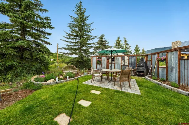 a view of house with a backyard and a patio