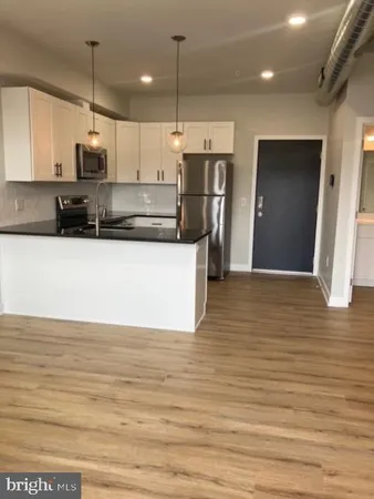 a kitchen with stainless steel appliances granite countertop a refrigerator a oven a sink and a wooden floors