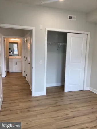 a view of a hallway with wooden floor and closet area