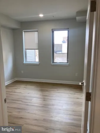 a view of an empty room with wooden floor and window