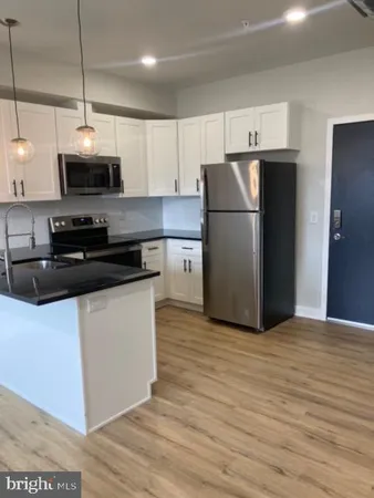 a kitchen with stainless steel appliances granite countertop a refrigerator a stove a microwave oven a sink and dishwasher with wooden floor